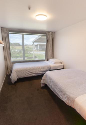two beds in a room with a large window at Riverstone House in Camerons