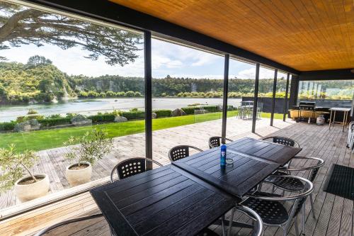 a wooden table and chairs on a deck with a large window at Riverstone House in Camerons