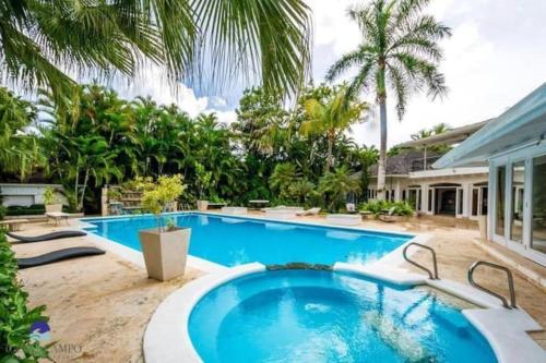 a swimming pool in front of a house with palm trees at Villa Beach & Golf CASA DE CAMPO in La Romana