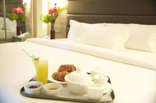 a tray with breakfast foods and a drink on a bed at Scarlet Lodge in Lagos