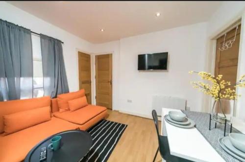 ein Wohnzimmer mit einem orangenen Sofa und einem Tisch in der Unterkunft Spacious one bedroom apartment in Reading