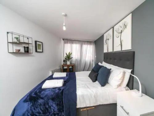 a bedroom with a large bed with a blue blanket at Spacious one bedroom apartment in Reading