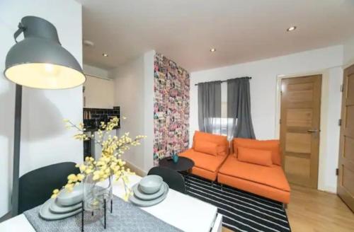 a living room with an orange couch and a table at Spacious one bedroom apartment in Reading