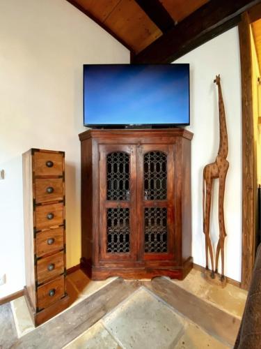 a room with a tv and a cabinet and a giraffe statue at Ferienhaus Namibia-Lodge im Rittergut Leppersdorf in Leppersdorf