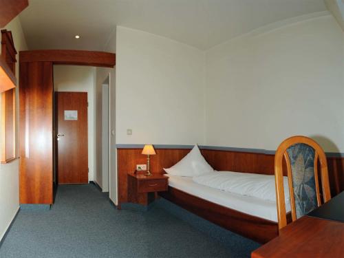 a bedroom with a bed and a table with a lamp at Hotel-Restaurant Thomsen in Delmenhorst