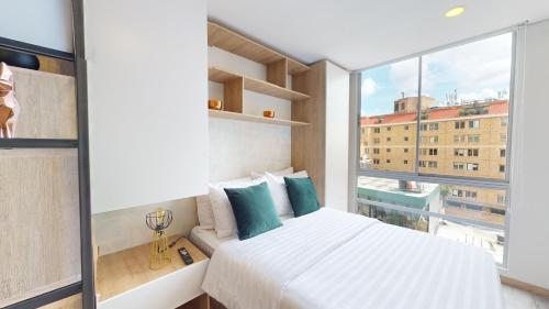 um quarto com uma cama branca e uma grande janela em Your Home in the Heart of Bogotá em Bogotá