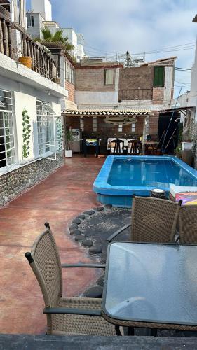 a patio with a table and chairs and a swimming pool at La isla surf Camp de punta hermosa in Punta Hermosa
