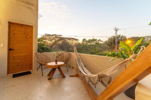 a hammock on a balcony with a table and chairs at Alma Tropical - Luxury Villa Experience in Santa Teresa in Santa Teresa Beach