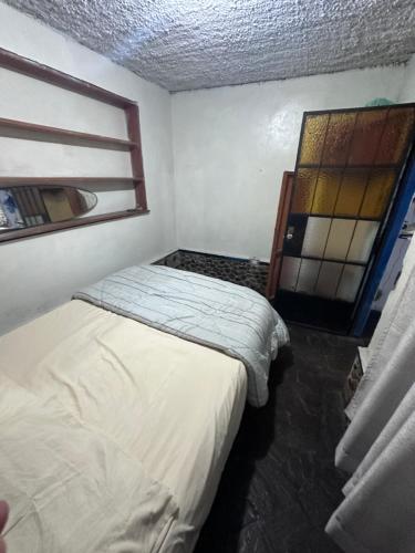 two beds in a small room with a window at La isla surf Camp de punta hermosa in Punta Hermosa