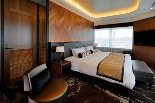 a hotel room with a bed and a chair at Hotel Monterey Himeji in Himeji
