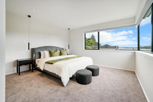 a bedroom with a large bed and a large window at Devonport Beach Front Home in Auckland