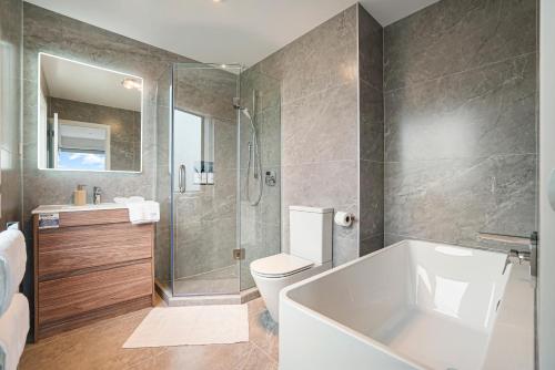 a bathroom with a tub and a toilet and a shower at Devonport Beach Front Home in Auckland