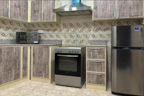 a kitchen with a stove and a refrigerator at MFAPARTMENT in Al Budayyiâ€˜