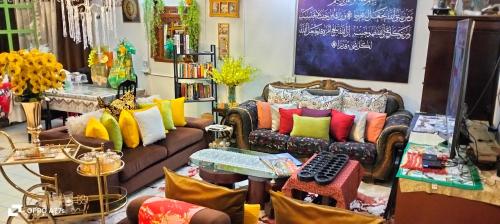 a living room with couches with colorful pillows at Forest Paradise Inn Teluk Bahang PRIVATE MALAY TRADITIONAL HOUSE CONCEPT HOTEL in Teluk Bahang