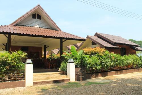 a house with a porch with a roof at Jim Guesthouse in Kanchanaburi