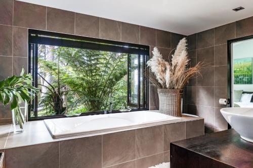 baño con bañera, lavabo y ventana en Mara Kai Retreat, en Raglan