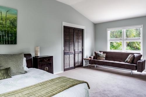 1 dormitorio con cama, sofá y ventana en Mara Kai Retreat, en Raglan