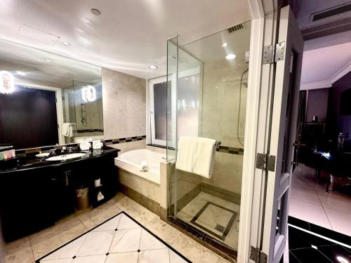 a bathroom with a shower and a tub and a sink at Royal Orchid Hotel Guam in Tumon