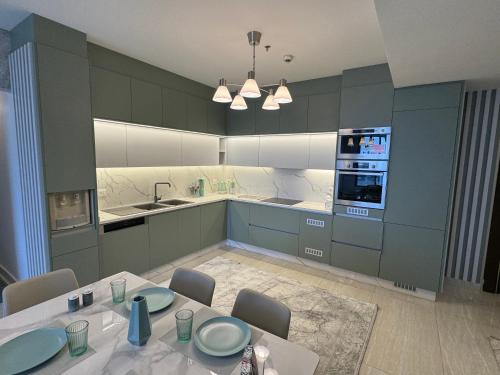 a kitchen with green cabinets and a table with chairs at Amazing brand-new apartment in Abdoun! in Amman