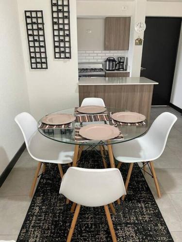 a dining room table with four chairs and a kitchen at Apartamento cómodo y exclusivo in Villa Nueva