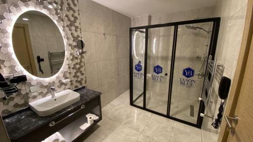 een badkamer met een douche, een wastafel en een spiegel bij YASON BLUE SUIT OTEL in Perşembe