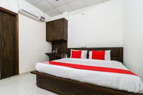 1 dormitorio con 1 cama grande con almohadas rojas en OYO Hotel Rk Inn, en Ludhiana