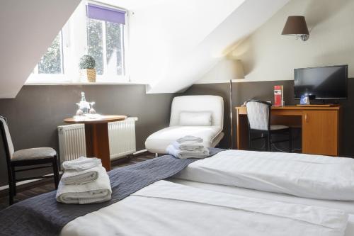 1 dormitorio con 2 camas, silla y TV en Dresdner Hof en Zittau