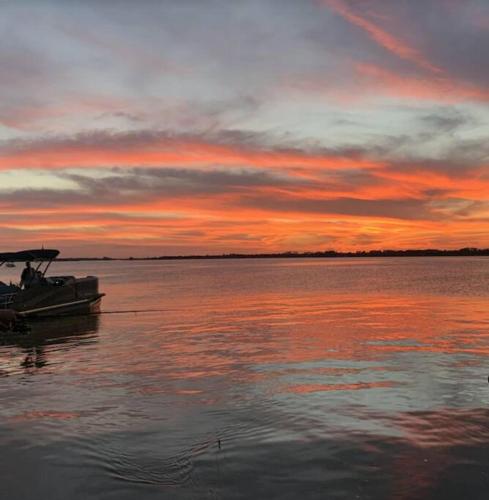a boat sitting on the water at sunset at Lakefront Duplex With Pontoon Boat 3 Bed House in Mount Dora