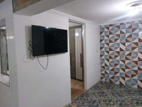 uma televisão de ecrã plano numa parede num quarto em Casa simples e aconchegante / Banho quente em Contagem