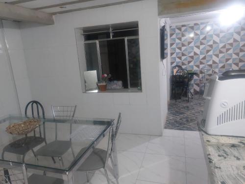 uma sala de jantar com uma mesa de vidro e uma janela em Casa simples e aconchegante / Banho quente em Contagem