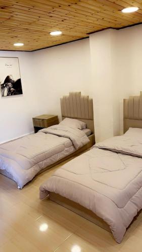 two beds are lined up in a room at شاليه نايا in Kerak