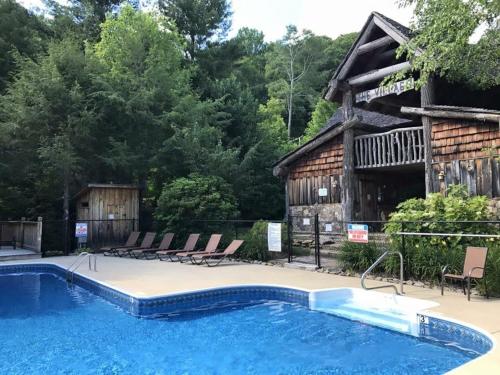 una piscina frente a una cabaña con sillas y una casa en Peak Living Mountain Home With Fireplace, en Swiss