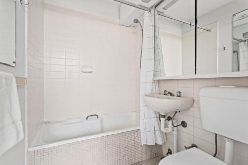 a white bathroom with a sink and a toilet at Apartment with Pool Access, a minute to the Beach in Sydney