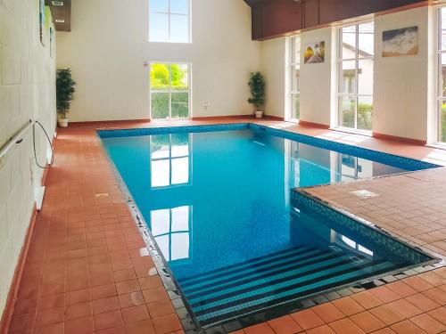 a large swimming pool with blue water in a building at The Popples in Ivybridge