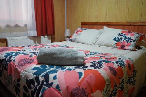 a bed with a colorful comforter with a pillow on it at Hostal Prat II in Valdivia