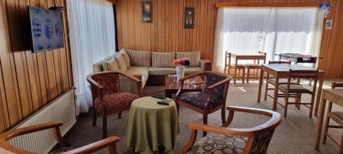 ein Wohnzimmer mit einem Sofa, Tischen und Stühlen in der Unterkunft Hostal Prat II in Valdivia