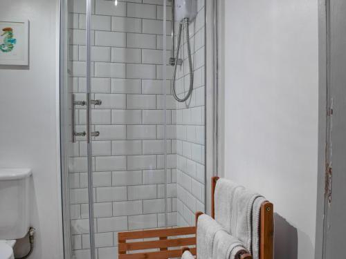 a bathroom with a shower with white tiles at Brook Farm Cottage in Nantwich