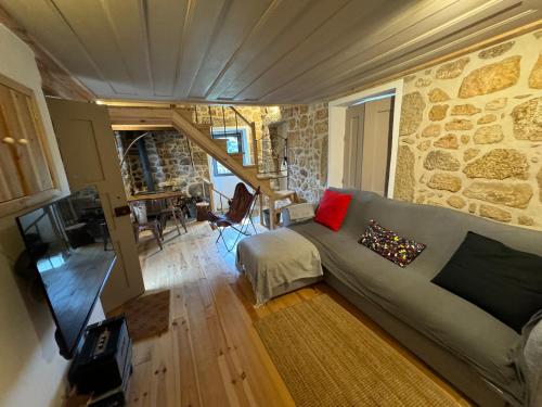 a living room with a couch and a stone wall at Cabana da Raposa in Oliveira do Hospital