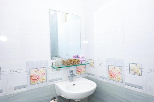 uma casa de banho branca com um lavatório e um espelho em Khách sạn Ciao Quy Nhơn em Quy Nhon
