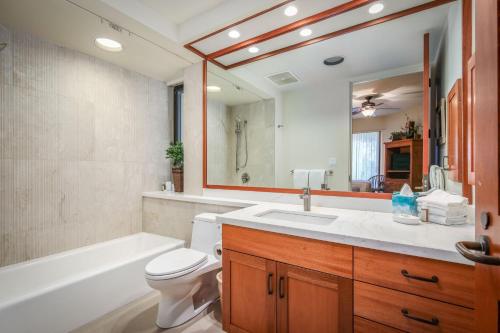 a bathroom with a toilet and a sink and a tub at Mauna Lani Point in Waikoloa