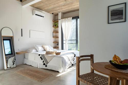 a bedroom with a bed and a table and a window at Alma Tropical - Luxury Villa Experience in Santa Teresa in Santa Teresa Beach