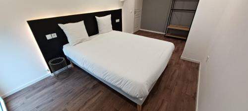 une chambre avec un grand lit avec des draps et des oreillers blancs dans l'établissement Magnifique loft jacuzzi et sauna Lanester-Lorient, à Lanester