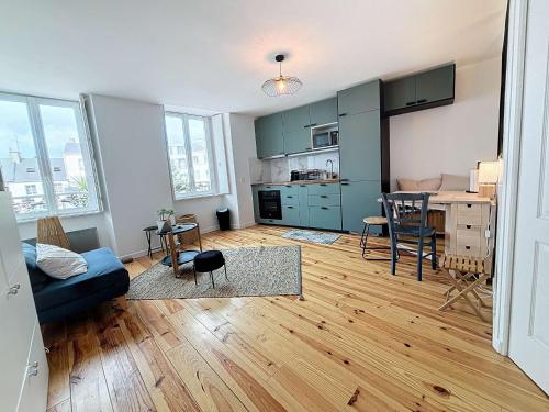 un salon avec un canapé bleu et une cuisine dans l'établissement Appartement rénové, 1 chambre, 300m de la gare, près du centre de Granville - FR-1-361-479, à Granville