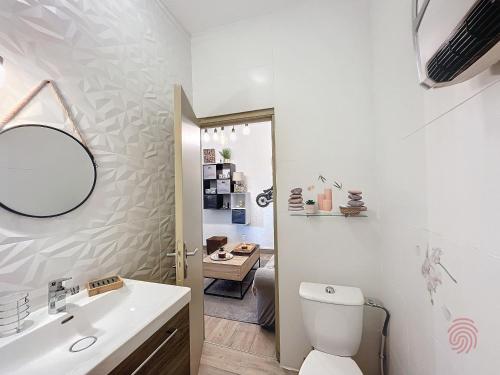 une salle de bain avec toilettes, lavabo et miroir dans l'établissement Appartement F2 avec terrasse, climatisation et proche des Thermes - Lamalou-les-Bains - FR-1-451-202, à Lamalou-les-Bains
