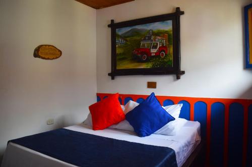 a bed with colorful pillows and a painting on the wall at FILANDIA HOTEL in Filandia