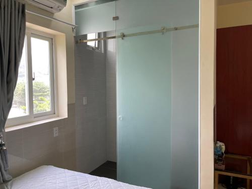 a bedroom with a shower and a bed and a window at Việt Nga Hotel - Chợ Côn Đảo in Con Dao