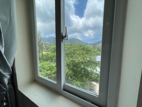 a window with a view of a tree at Việt Nga Hotel - Chợ Côn Đảo in Con Dao