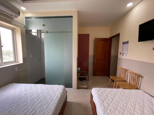 a bedroom with two beds and a sliding glass door at Việt Nga Hotel - Chợ Côn Đảo in Con Dao