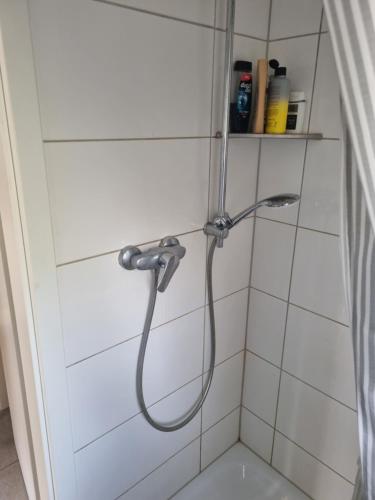 a shower with a hose in a white tiled bathroom at Hörster Horst in Lage