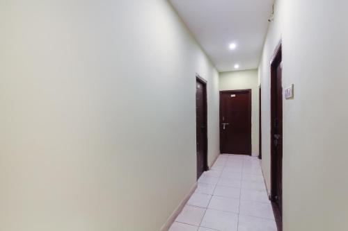 a hallway with black doors and white tile floors at SPOT ON 9 Star Guest House in Kondapur